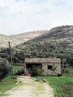 Two mountains with Israeli settlements and a Palestinian house in the foreground